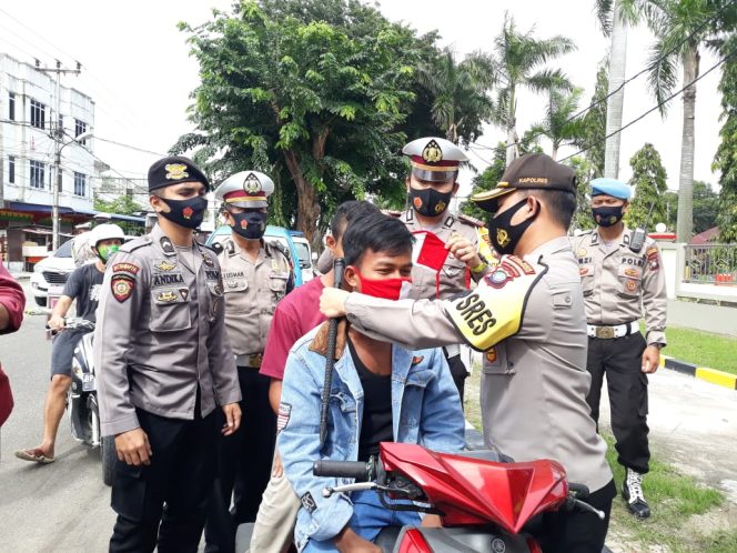 
 Kapolres Karimun, AKBP M Adenan memasangkan masker pada salah satu pengendara yang tidak memakai helm dan masker (yan)