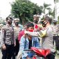 Kapolres Karimun, AKBP M Adenan memasangkan masker pada salah satu pengendara yang tidak memakai helm dan masker (yan)