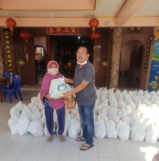 
 Pengurus Yayasan Cetiya Dharma Sagara Kabupaten Karimun, Awi saat membagikan paket sembako kepada salah seorang warga yang kurang mampu 