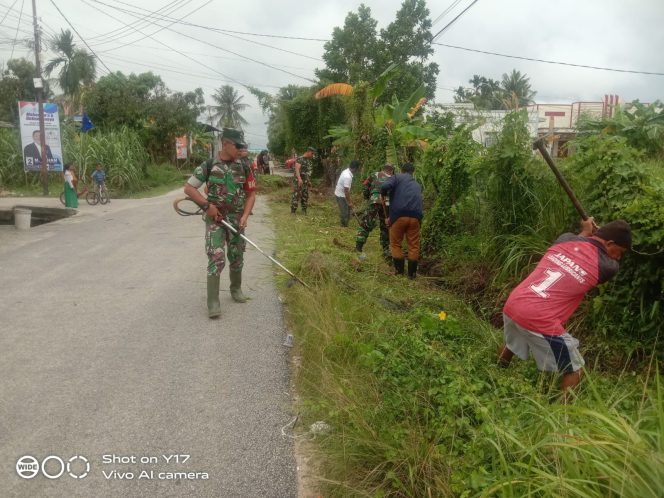 
 Babinsa Koramil 01 Balai Goro Bersama Warga Bersihkan Rumput Liar dan Parit